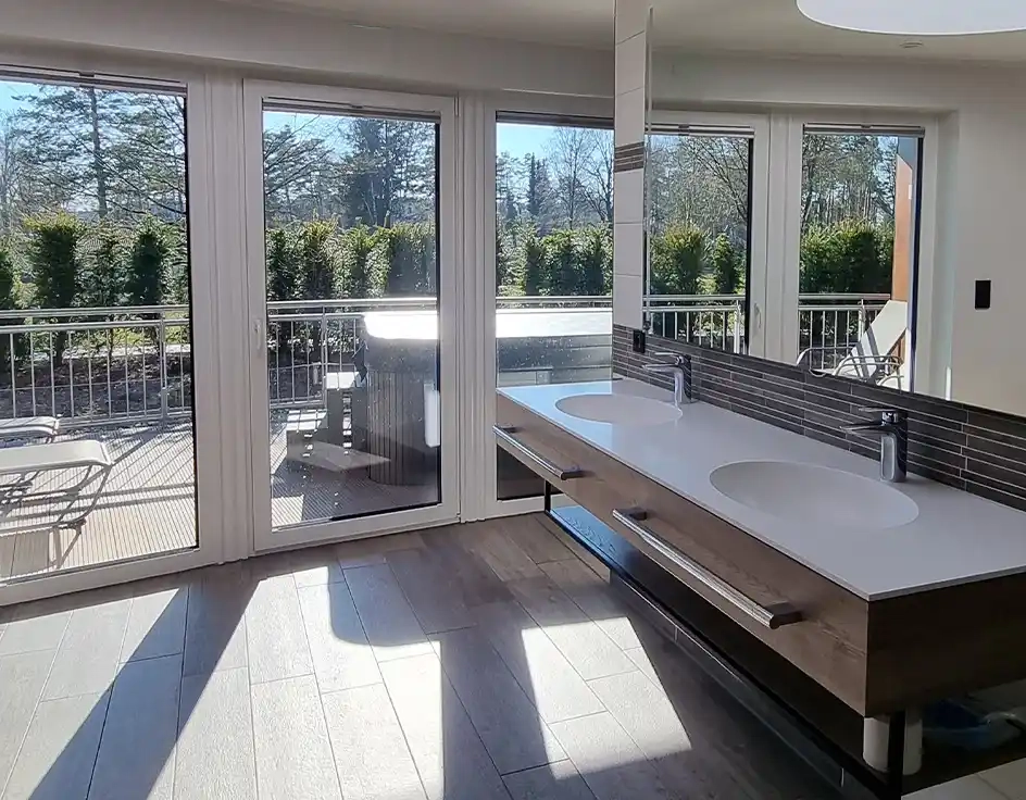 Sanitary buildings in the Südsee-Camp Modern private bathroom in sanitary building 4 at Südsee-Camp, featuring two sinks, a large mirror wall, and direct access to a private outdoor terrace with privacy screen and hot tub.