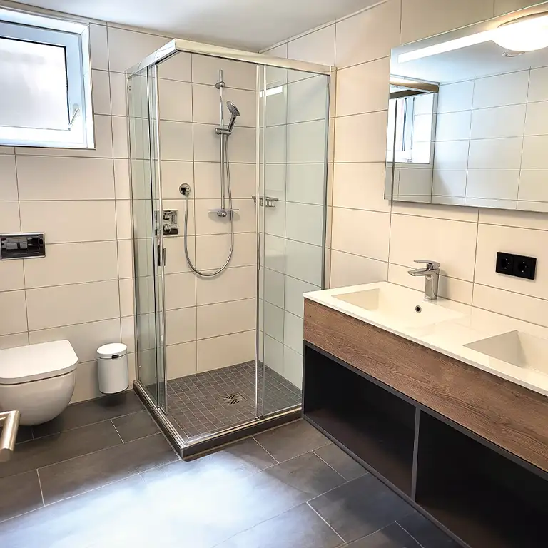 Modern private bathroom of the standard category in washhouse 10 at Südsee-Camp featuring a shower, double sink, and toilet.