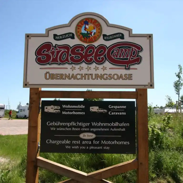 Information sign at Südsee-Camp with welcome message and details about the chargeable motorhome rest area