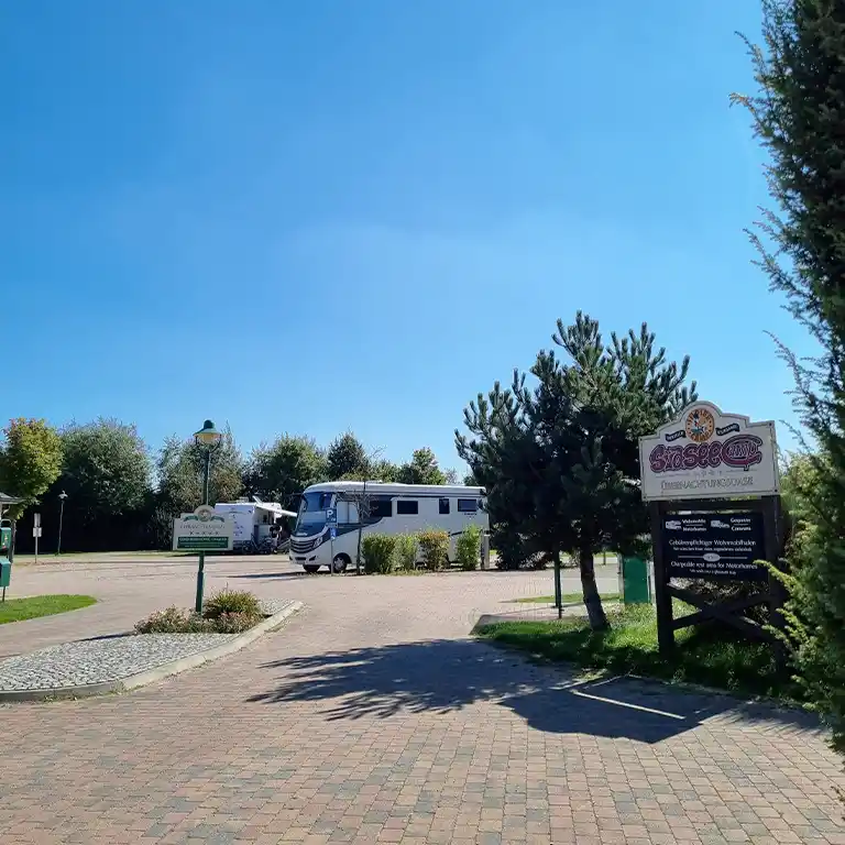 to the pitch area in front of the Südsee-Camp Entrance to the motorhome area at Südsee-Camp with signpost and parked motorhomes