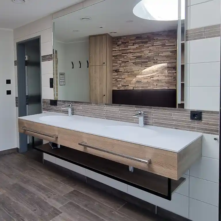 Modern private bathroom in sanitary building 4 at Südsee-Camp featuring two sinks, a large mirror, wood-style finish, and visible door to a separate toilet.