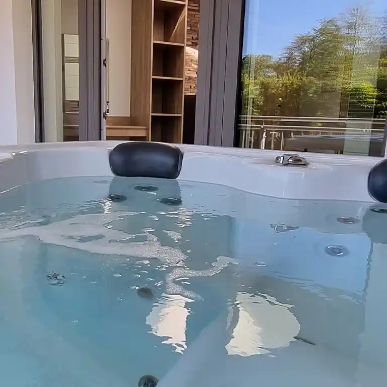 Whirlpool on the private rooftop terrace of a private bathroom at Südsee-Camp, with a view of greenery and interior in the background.