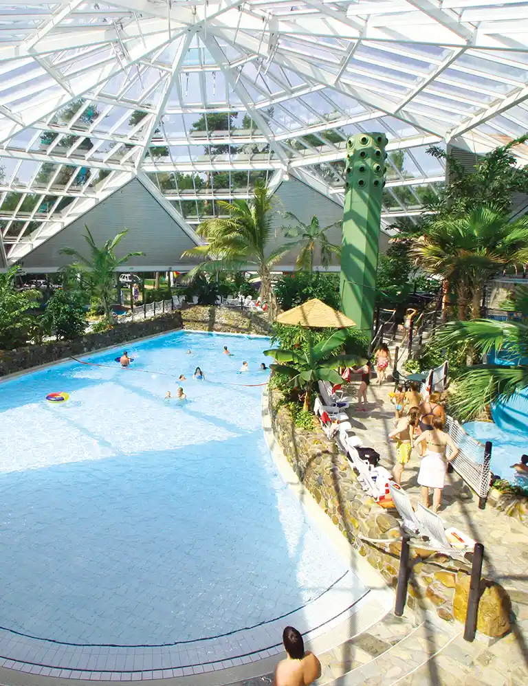 Tropisch gestaltetes Hallenbad mit Palmen, Kuppeldach und Badenden