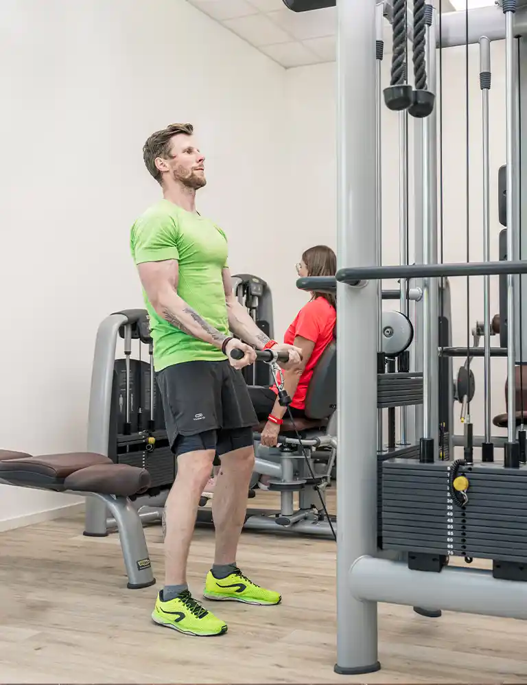 Zwei Personen trainieren an modernen Kraftgeräten im Fitnessraum