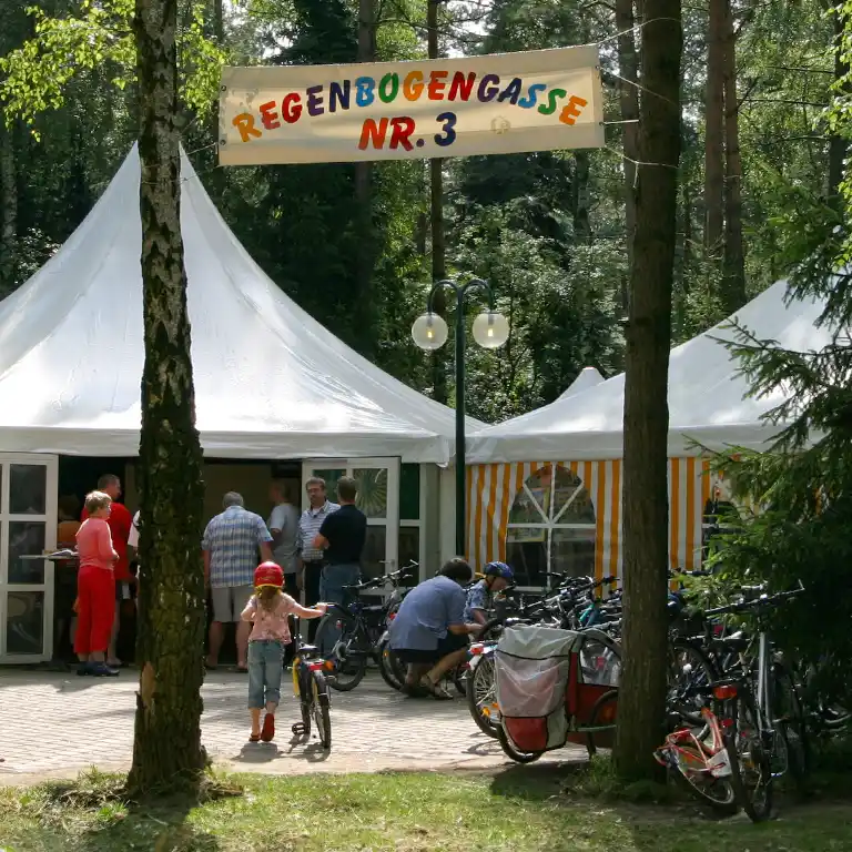 Zeltbereich der mobilen „Kirche unterwegs“ mit Fahrrädern und Besuchern im Wald