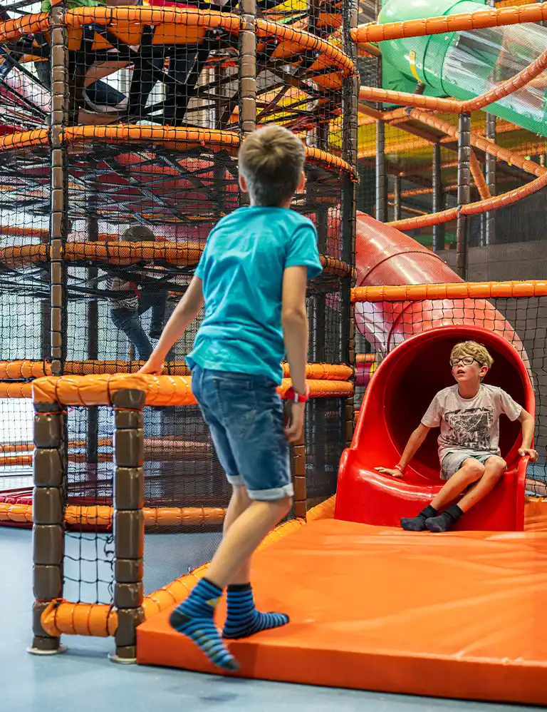 Kinder im bunten Kletter- und Rutschbereich des Indoor-Spielplatzes