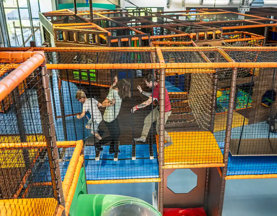 Children climbing and playing in the large indoor playground at Südsee-Camp – safe fun no matter the weather.