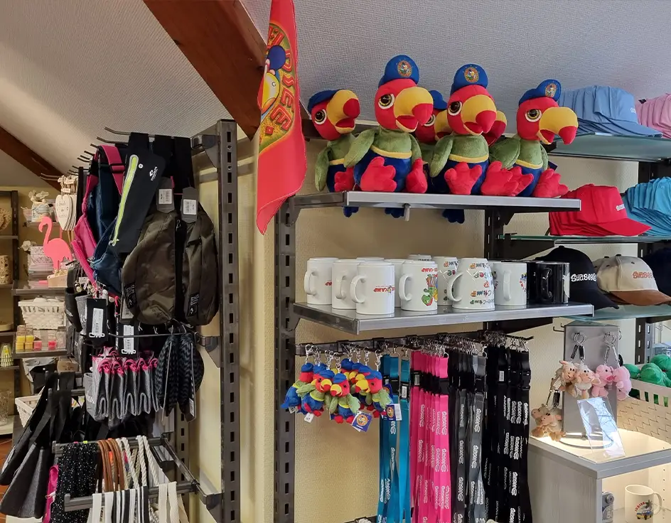 Shops at the Südsee-Camp Souvenirs at the Südsee-Trends shop in Südsee-Camp – colorful shelves with Campino plush toys, mugs, keychains, baseball caps, and backpacks