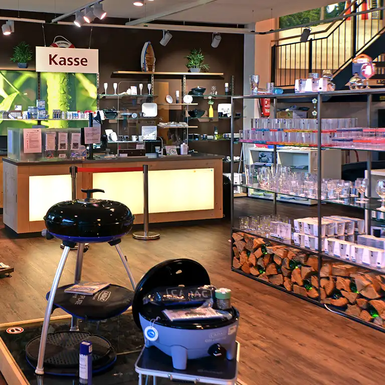 Interior view of the camping shop at Südsee-Caravans featuring barbecue equipment, tableware, glasses and checkout counter – everything for a perfect camping holiday